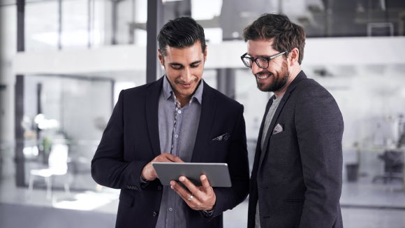 Shot of two young businessmen using a digital tablet together in a modern office