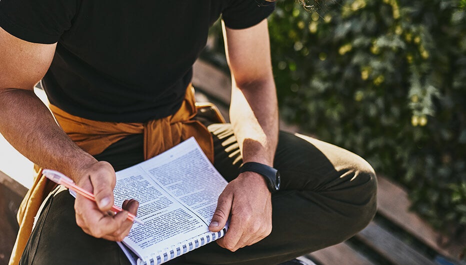 man taking notes crosslegged 