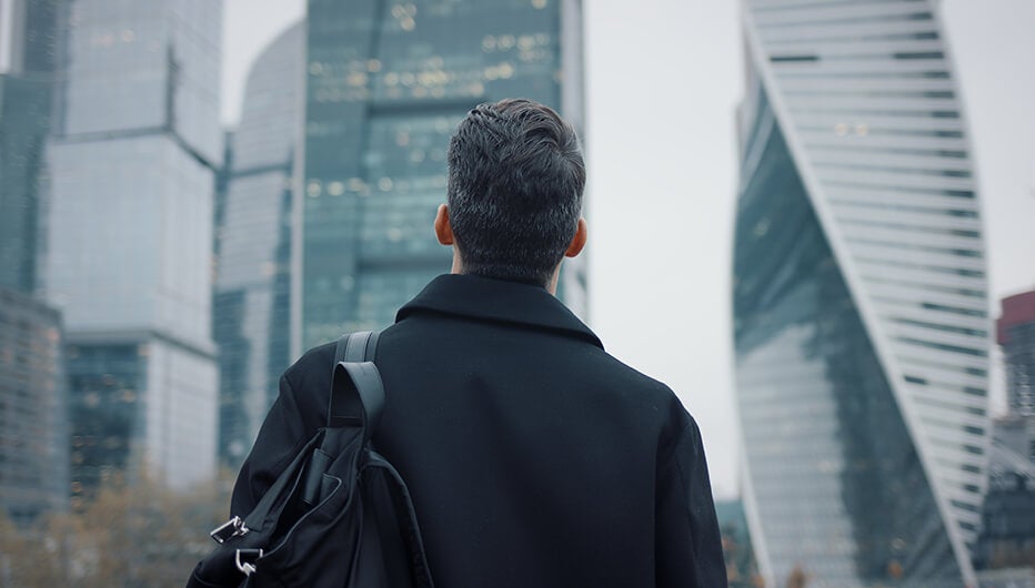 man in city looking at skyscrapers 