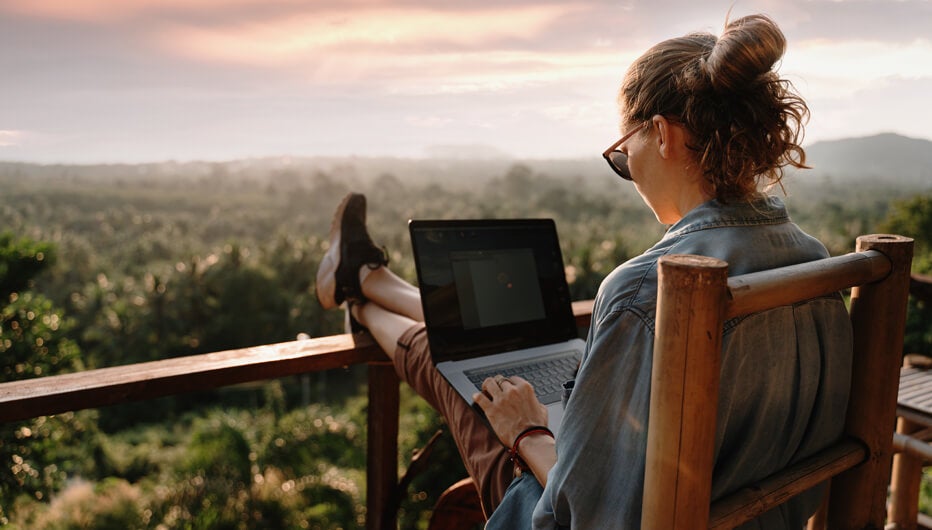 woman on balcony with feet up and laptop