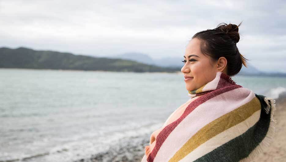 woman looking at lake with blanket over shoulders
