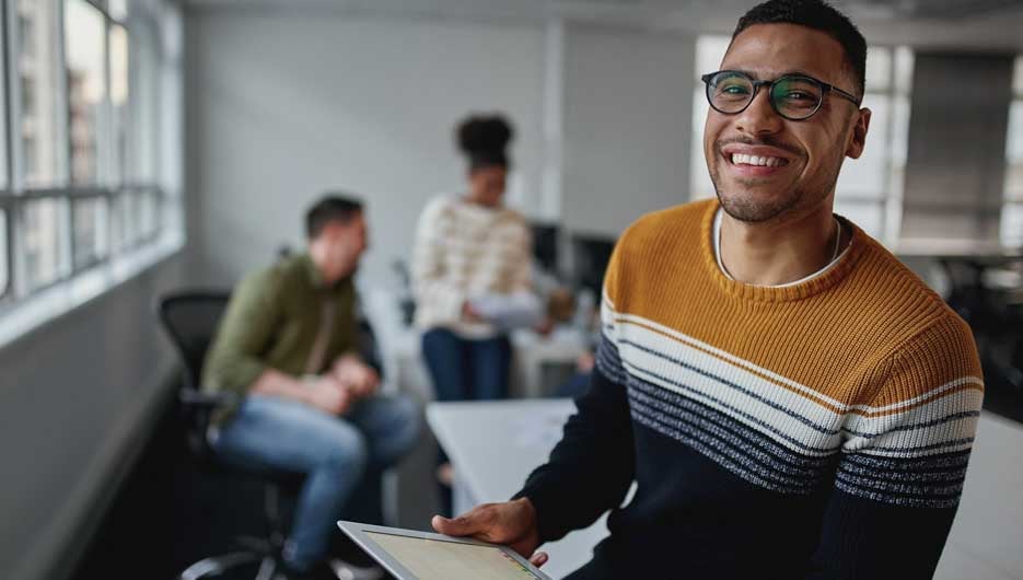 Smiling young businessman with digital tablet at workplace